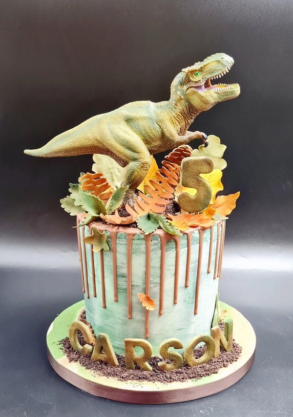 Drip cake with toy dinosaur on top