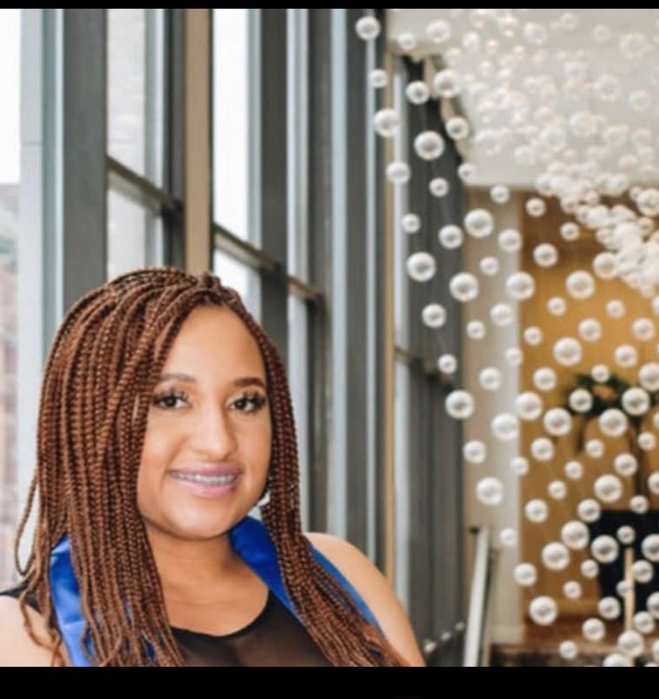 Smiling woman with braided hair and braces inside a modern building.