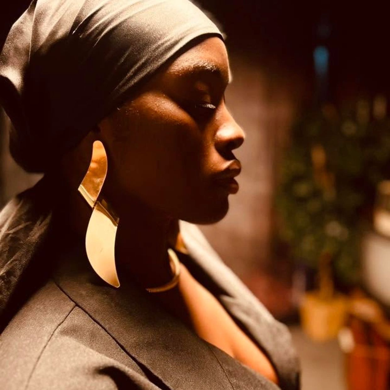Profile of a woman with a head wrap and large earrings.