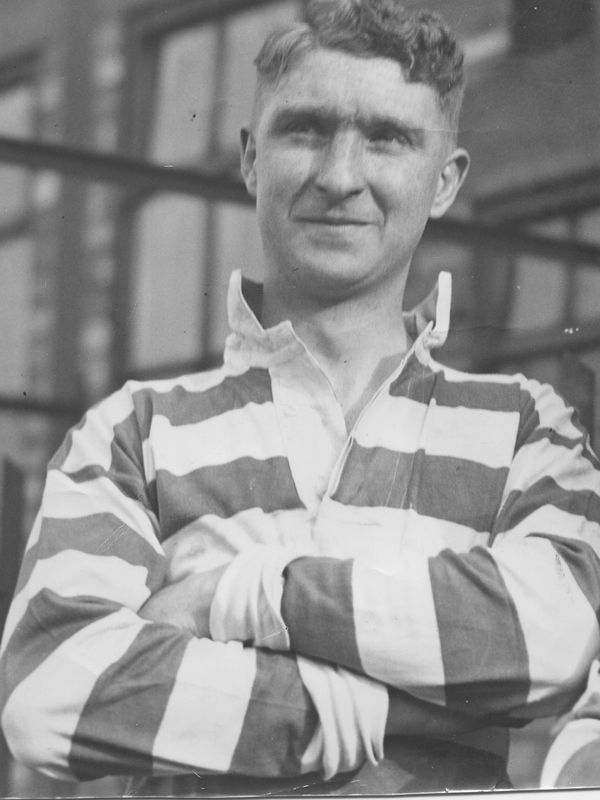 Young man in a striped shirt with arms crossed, looking confident.