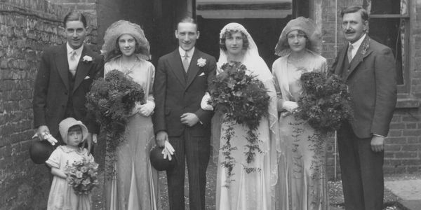 Black and white vintage wedding photo with bride, groom, and attendants.