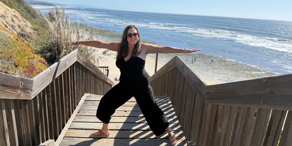 Woman posing on wooden stairs by the beach.