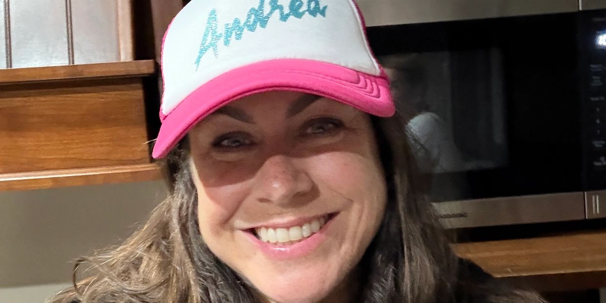 Smiling woman wearing a pink and white cap that says Andrea.