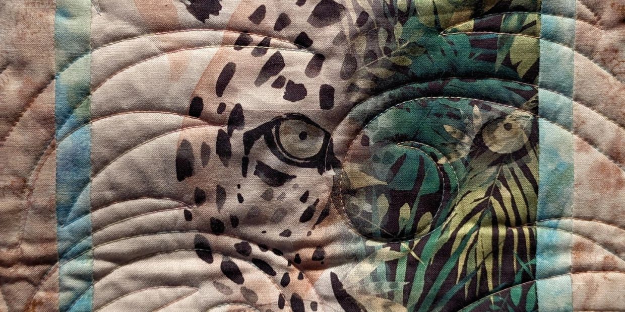 Close-up of a quilt with animal prints and stitched patterns.