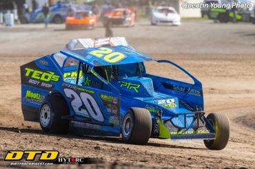 Blue dirt track race car number 20 speeding on a dirt track.