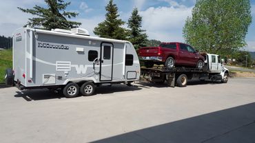A white travel trailer being towed by a truck.