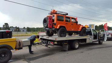 Orange SUV being loaded onto a tow truck.