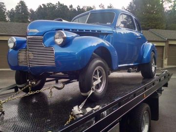 Blue vintage car on a flatbed truck.