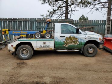 Tow truck parked on dirt beside fence.