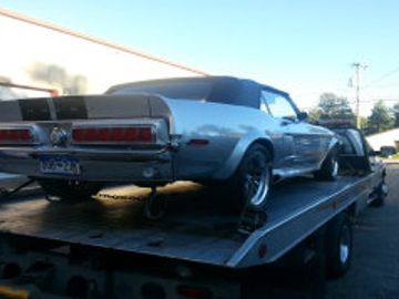 Silver vintage Mustang on a flatbed truck.