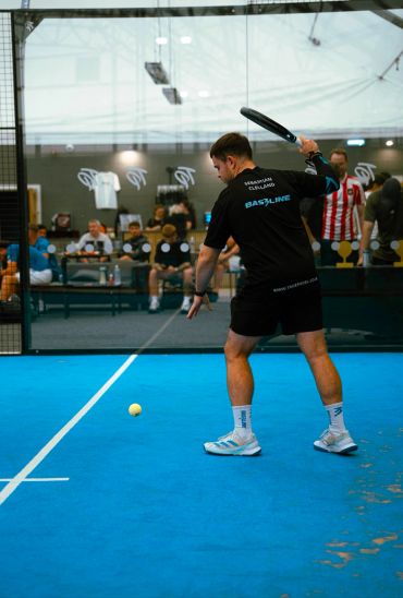 Player preparing to hit the ball in a paddle tennis match.