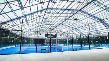 Indoor paddle tennis courts under a glass roof.