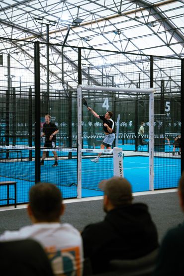 Players competing in a padel match inside an indoor court.