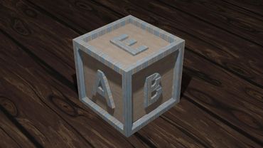 Wooden toy block with letters A, B, and E on a dark wooden floor.