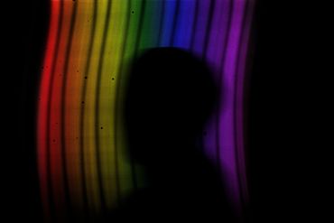 Blurry figure fading into darkness with a rainbow streaks behind them