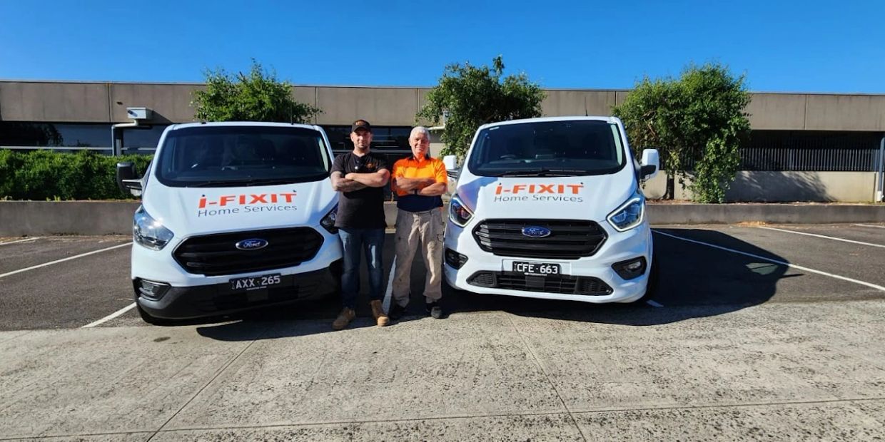 Two men standing with i-FIXIT Home Services vans.