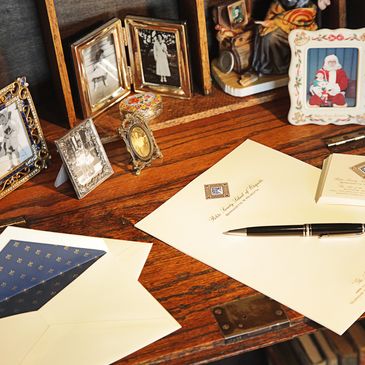 A wooden desk with vintage photos, letters, and a pen.