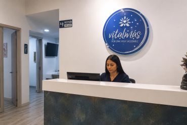 Receptionist at Vitalnias clinic front desk working on computer.