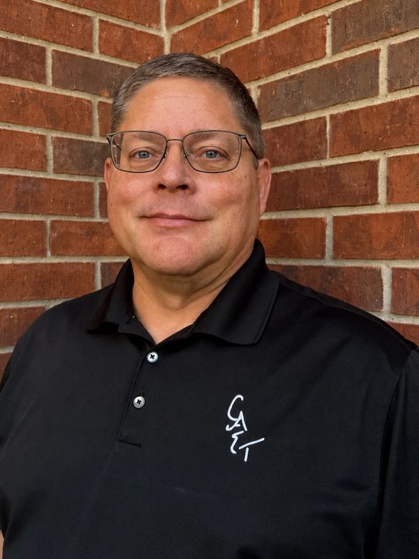 Middle-aged man wearing glasses and a black polo shirt.