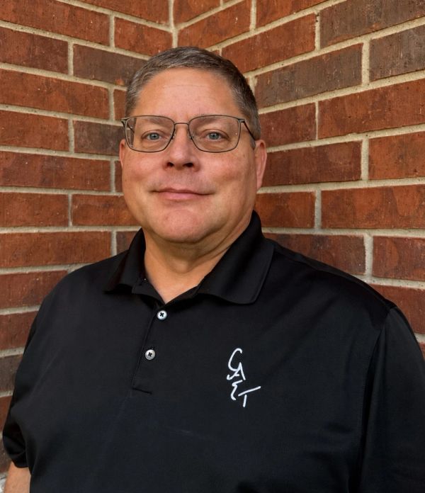 Middle-aged man wearing glasses and a black polo shirt.