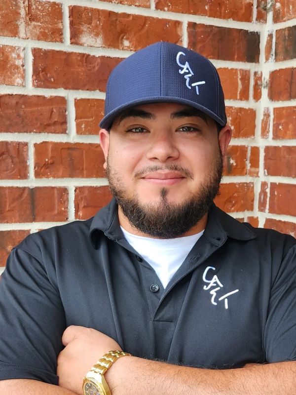 Man wearing a black shirt and blue cap with "CALI" logo.