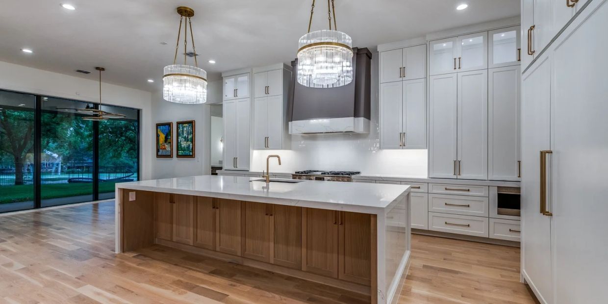 Modern kitchen with large island, white cabinets, and elegant pendant lights.