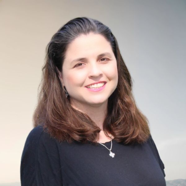 Smiling woman with long brown hair in a black top against a soft gradient background.