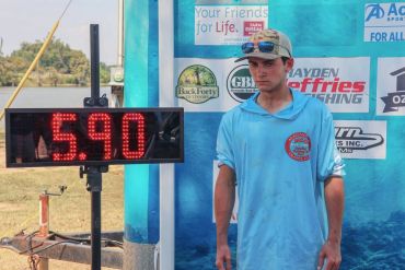 A man stands next to a digital fish weight display showing 5.90.