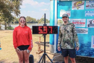Two people stand beside a digital timer showing 5:17.