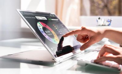 Person interacting with a touchscreen laptop displaying colorful data charts.