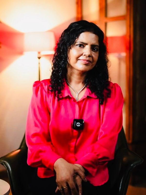 A woman in a bright pink blouse sitting indoors with soft lighting.