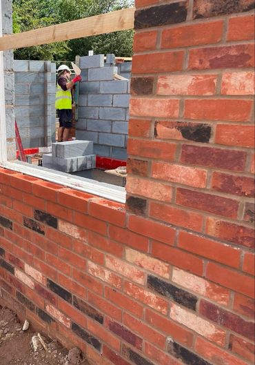 Red brick new build house and block work with one of the team working in the background