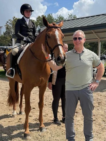 Person on horseback with two others nearby on a sunny day.