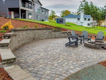 Outdoor patio area with stone pavers, retaining walls, and seating around a fire pit in Edmonton