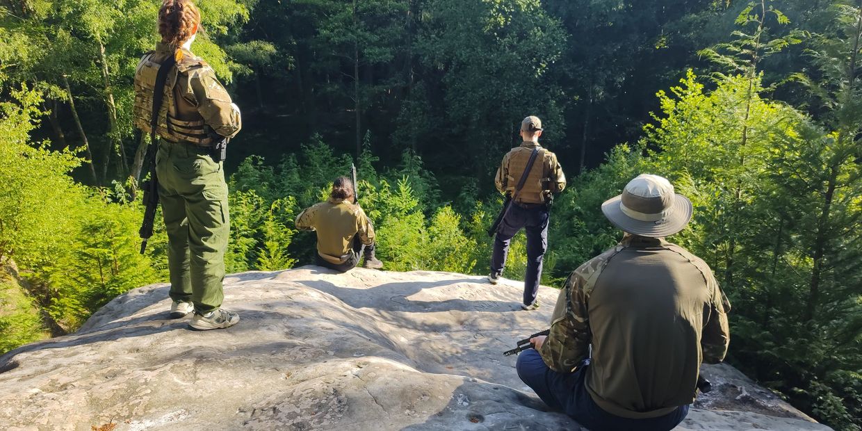 Stunt performers take a break from Theatrical firearms training in summer sunshine.