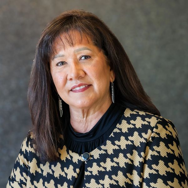 Professional woman in a patterned blazer with a warm smile.