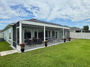 Backyard patio with screened enclosure and outdoor seating.