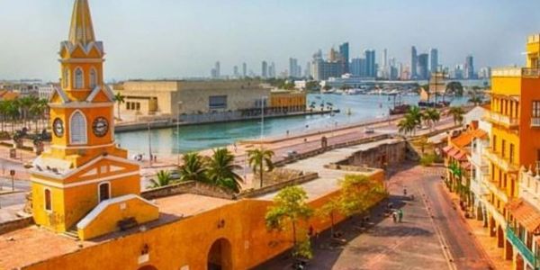 Historic cityscape with a clock tower and waterfront, blending old architecture and modern skyline.