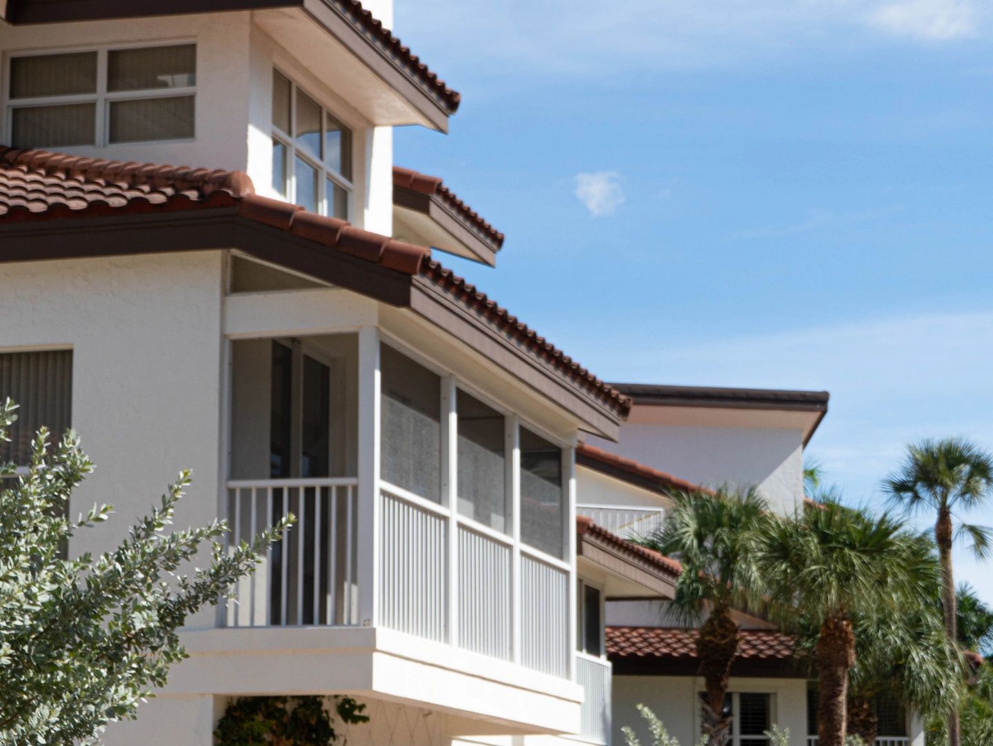 Modern residential building with tiled roofs and screened balconies.