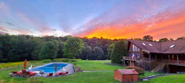 Sunset over luxury Catskills chalet, heated pool, and private mountain grounds