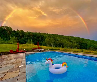 Heated pool and spillover spa with rainbow and mountain views at a private Catskills wedding venue