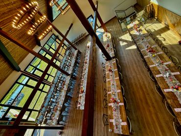 Elegant rustic dining setup with long wooden tables and floral decorations in a spacious hall.
