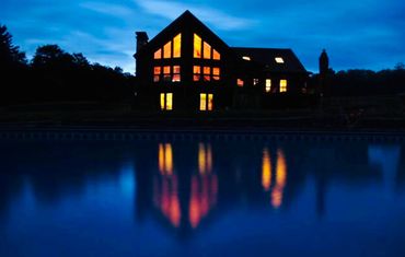 Catskills mountain lodge at night reflected in the pond at a private wedding venue