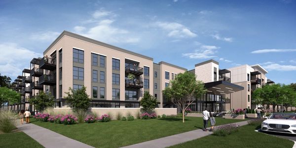 Modern apartment complex with balconies and landscaped greenery under a clear blue sky.
