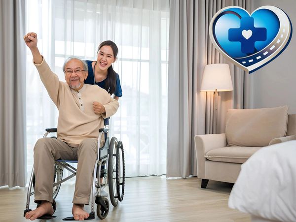 Happy elderly man in wheelchair with smiling caregiver indoors.