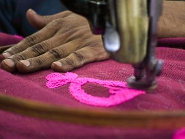 The image shows a close-up of hands operating what appears to be a specialized sewing