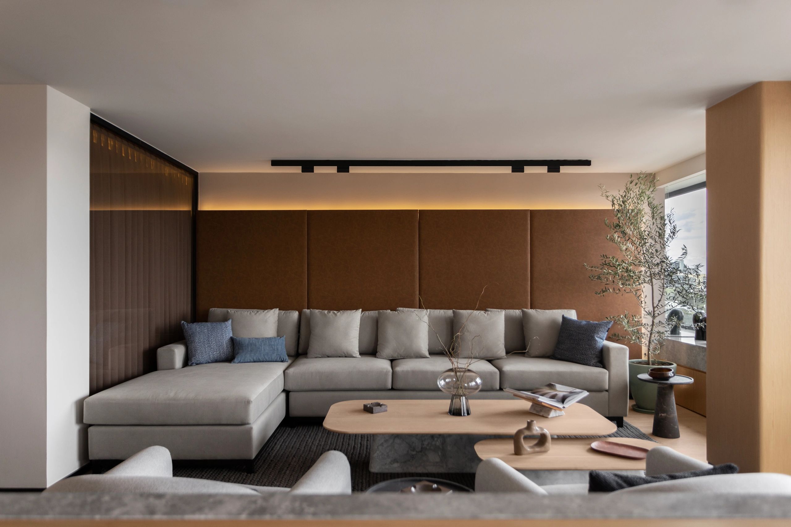 Sala moderna con sofá gris y detalles en tonos marrones y azules.