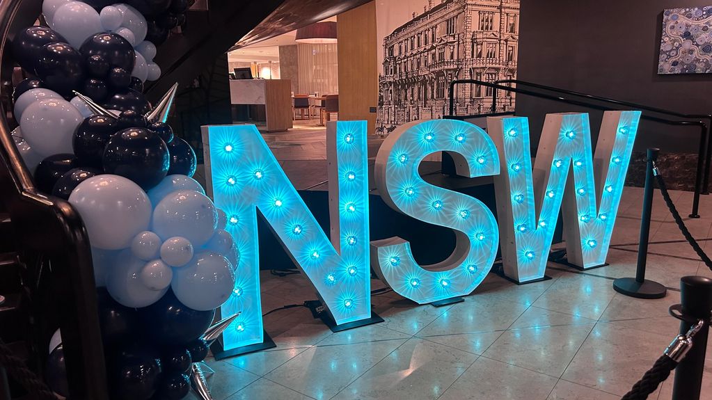 Illuminated NSW letters with black and light blue balloons.