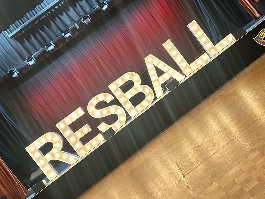 Illuminated letters spelling 'RESBALL' on a stage.