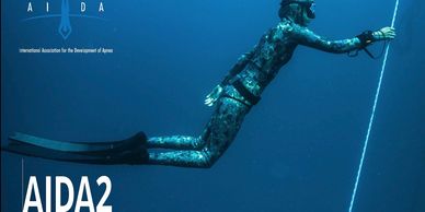 Freediver underwater holding a rope.